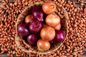 Onions in a basket with red onions top view on a shallots background